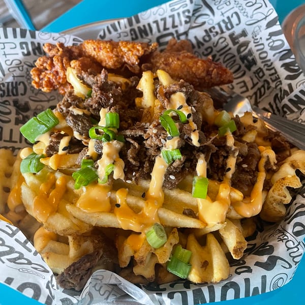 Waffle fries topped with bulgogi beef, spicy mayo, sesame seeds, and green onions, with fried chicken.